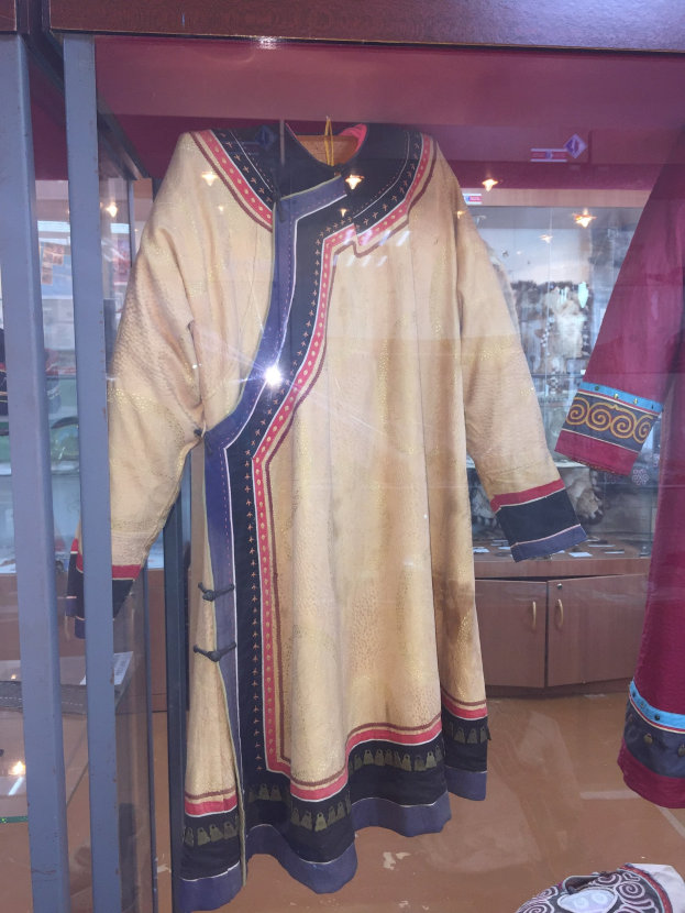 Vitrine mit verschiedenen Kostümen aus *Der König der Löwen*, darunter eine Schaufensterpuppe in einem Kleid und einer Kappe, sowie andere themenbezogene Gegenstände.
