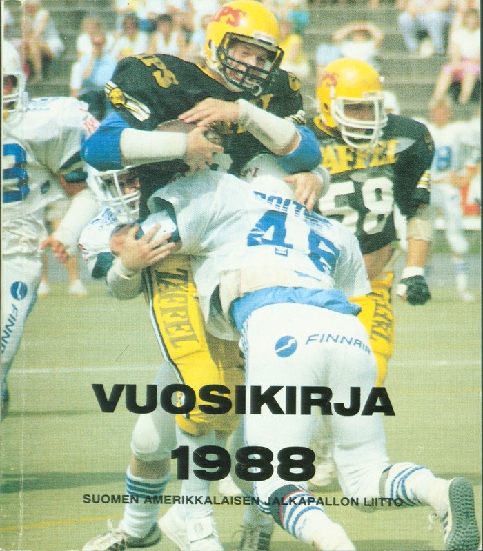 Gruppe von Menschen in Sportkleidung und Helmen, die Fußball spielen, mit Zuschauern auf einer Treppe im Hintergrund; Text unten lautet "Vuosikirja 1988 - Suomen Amerikkaisen Jalkapallon Litto".