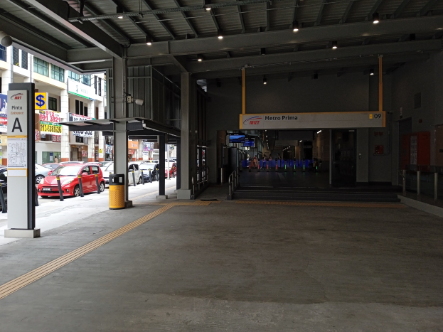 Leerer Parkhaus mit geparkten Autos, Betonpfeiler, Informationsschilder, Deckenbeleuchtung und Gebäuden mit Fenstern im Hintergrund.