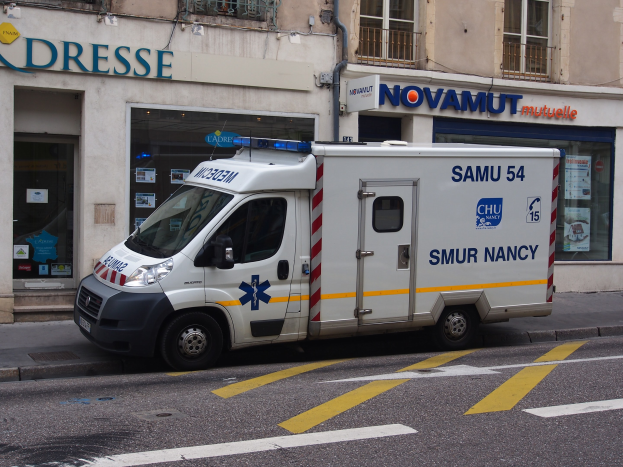 Ambulanz vor einem Gebäude mit Krankenhausschilderung und Plakaten geparkt