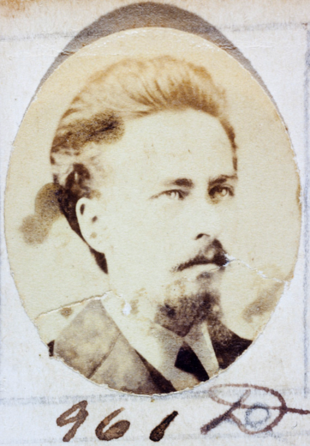 Ein altes Foto eines Mannes mit Schnurrbart und Bart, der direkt in die Kamera schaut und ernst und nachdenklich aussieht.