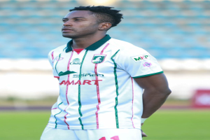 Der ghanaische Fussballspieler Emmanuel Adebayor steht auf einem Fussballfeld und trägt ein weisses und grünes T-Shirt und Shorts.