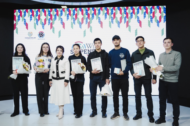 Gruppe von Menschen auf einer Bühne mit Bücher und Blumensträußen, im Hintergrund ein Bildschirm mit der Aufschrift "Yogyakarta International School of Science and Technology"