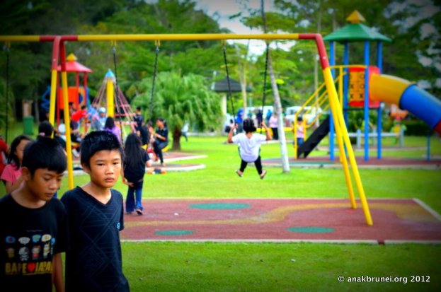Kinder auf Spielgeräten im Park umgeben von Bäumen