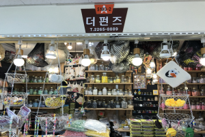 Ein Geschäft mit verschiedenen Artikeln wie Körben, Lampen, Flaschen und Spielzeugen, die auf Regalen angeordnet sind, mit einem Schild oben, das es als eines der besten koreanischen Geschäfte in Seoul ausweist.