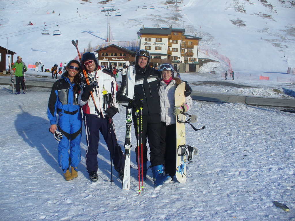 Vier Personen posen für ein Foto mit Skating-Pads und Werkzeugen vor einer verschneiten, eisigen Berglandschaft.