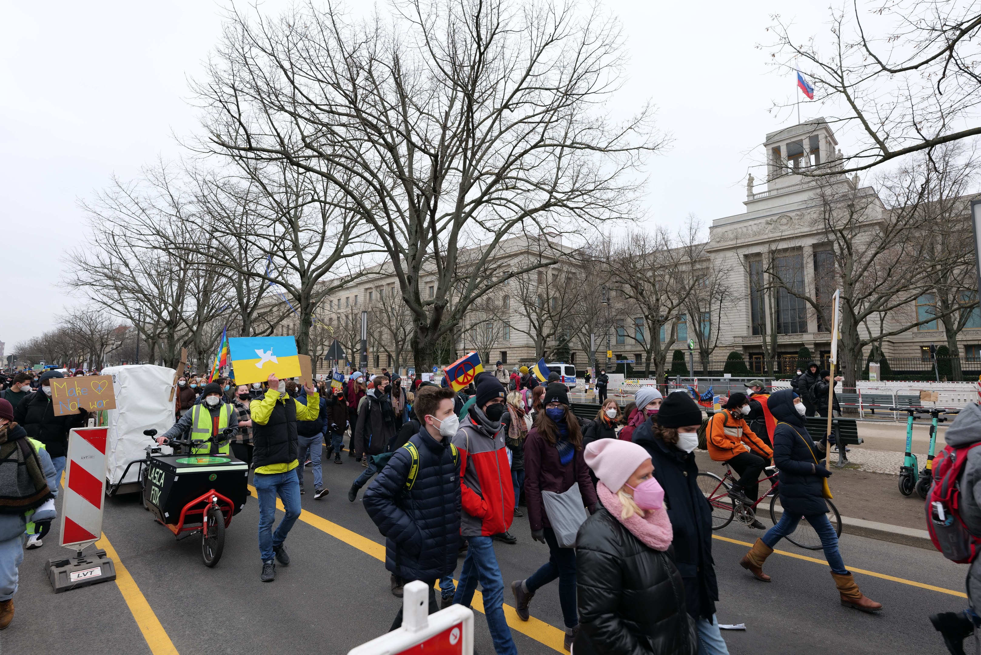 Eine große Gruppe von Menschen marschiert bei einer Demonstration in Washington, D.C. am 21. Januar 2020 mit Plakaten, Schildern und Fahrrädern die Straße entlang, mit Bäumen, Schildern und einem klaren blauen Himmel im Hintergrund.