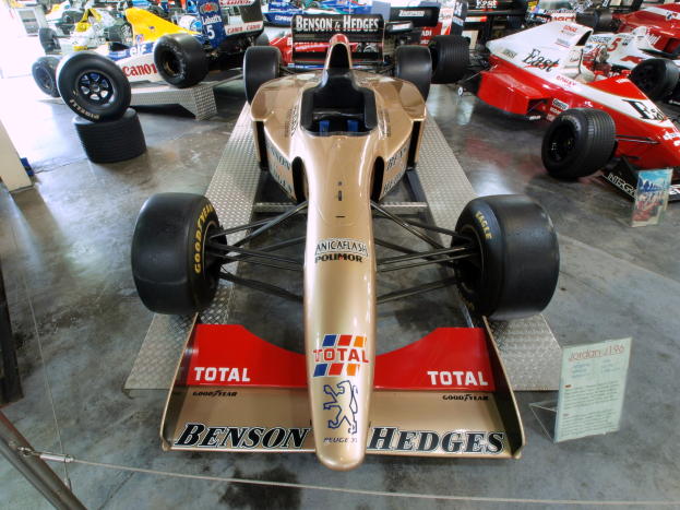 Rennwagen in einem Motorsportmuseum ausgestellt, getrennt durch einen Metallzaun mit Informationsschilder