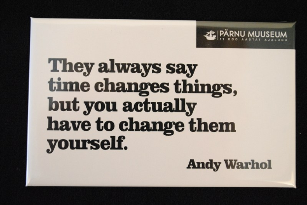 Whiteboard mit schwarzem Hintergrund, das das Zitat "Sie sagen immer, die Zeit verändert die Dinge, aber man muss sie selbst verändern." anzeigt.