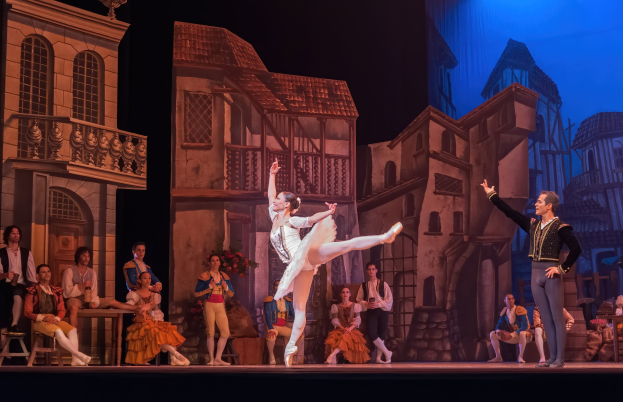 Zwei Tänzer performen auf einer Bühne in der Royal Opera House in London, mit einem Publikum, das im Vordergrund sitzt und steht.