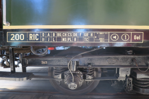 Ein Nahaufnahme eines Zugwagens auf Schienen, der seine Räder und Bremse zeigt, was darauf hindeutet, dass der Zug in Bewegung ist.