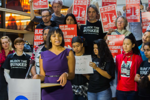 Eine Black-Lives-Matter-Aktivistin spricht in ein Mikrofon auf einem Podium und wendet sich an eine Menge mit Schildern.