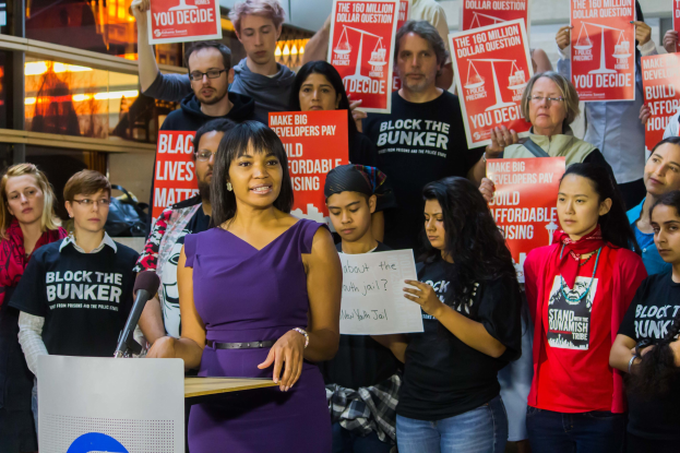 Eine Black-Lives-Matter-Aktivistin spricht in ein Mikrofon auf einem Podium und wendet sich an eine Menge mit Schildern.
