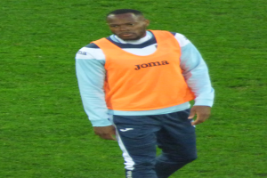 Ein Mann in einem orangen T-Shirt und blauen Hosen durchquert entschlossen ein saftig grünes Feld.