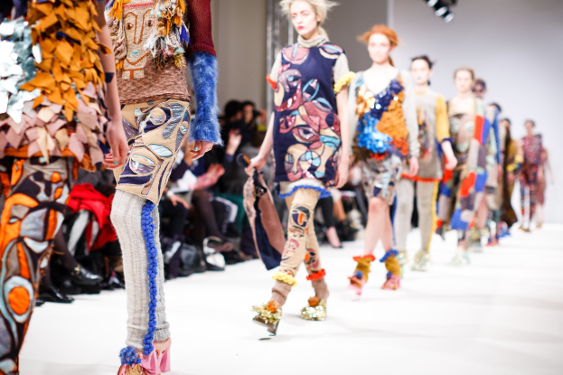 Frauen Gehen Auf Einer Laufsteg In London Fashion Week, Mit Einer Zuschauerschaft Im Hintergrund Unter Hellter Licht.