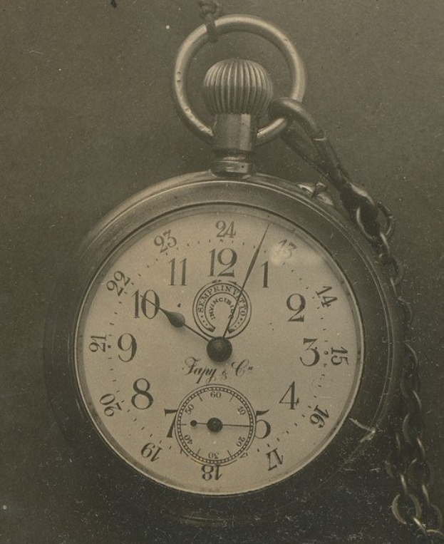 Altes Schwarz-Weiß-Foto einer Taschenuhr mit einer Kette, das eine nummerierte Zifferblatt zeigt.