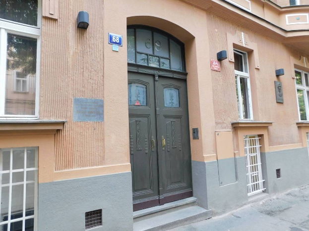 Ein Geb├Ąude mit einer gr├╝nen T├╝r und Fenstern, das an einer Stra├če mit einem Gehweg steht und Schilder und Lichter zeigt, die darauf hinweisen, dass es eine Wohnung zum Verkauf in der Innenstadt ist.