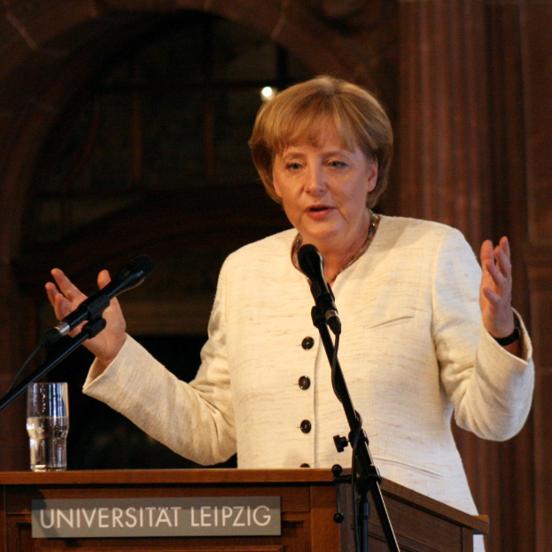 Bundeskanzlerin Angela Merkel hält eine Rede an einem Podium mit einem Mikrofon und einem Glas Wasser an der Universität Leipzig.