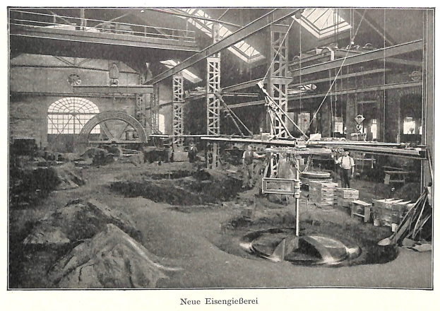 Schwarz-weißes Foto einer Fabrik mit Arbeitern, die Maschinen bedienen, umgeben von Metallstangen und -pfählen, beschriftet mit "Neue Eisenglebeerei, die erste Fabrik Deutschlands."