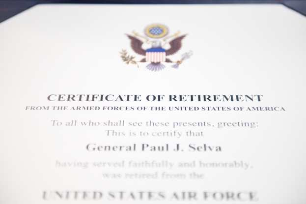 Blauer Rahmen mit einem Abschiedszeugnis der United States Air Force, das ein zentrales Sternschild-Logo innerhalb eines Lorbeerkranzes und eine 'Retirement'-Bannerschrift in schwarzer Schrift enthält.