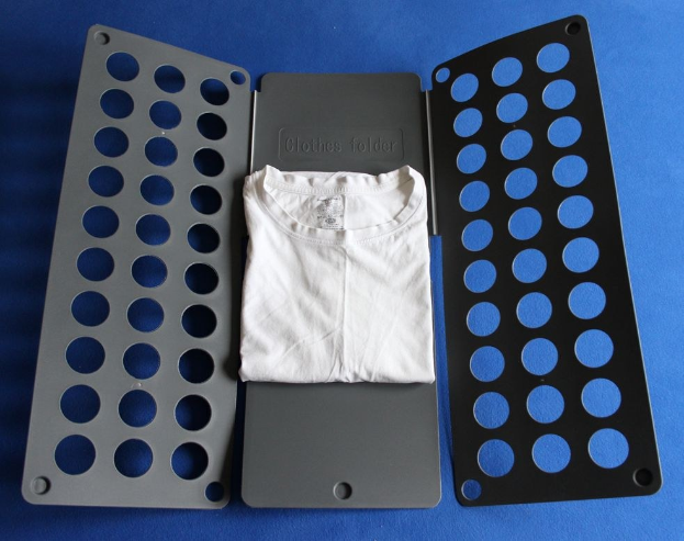 Weißes T-Shirt auf einer blauen Oberfläche neben einem schwarzen und aschfarbenen Kleiderordner mit mehreren Löchern.