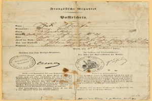 Ein altes, gelbliches Dokument mit einem kreisförmigen, schwarz umrandeten Stempel, wahrscheinlich ein Brief von der deutschen Regierung, mit schwarzer Tinte.